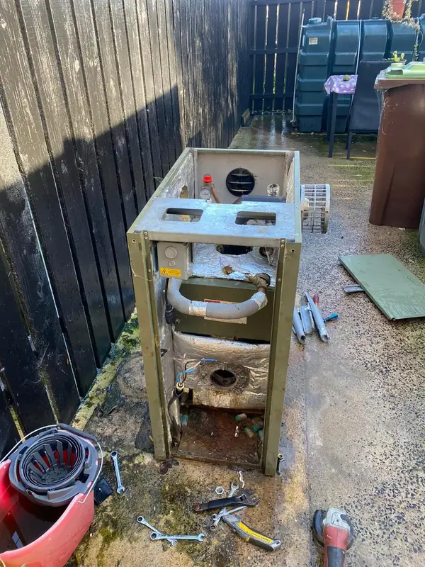 Old oil boiler with its casing off, tools laid out on the ground
